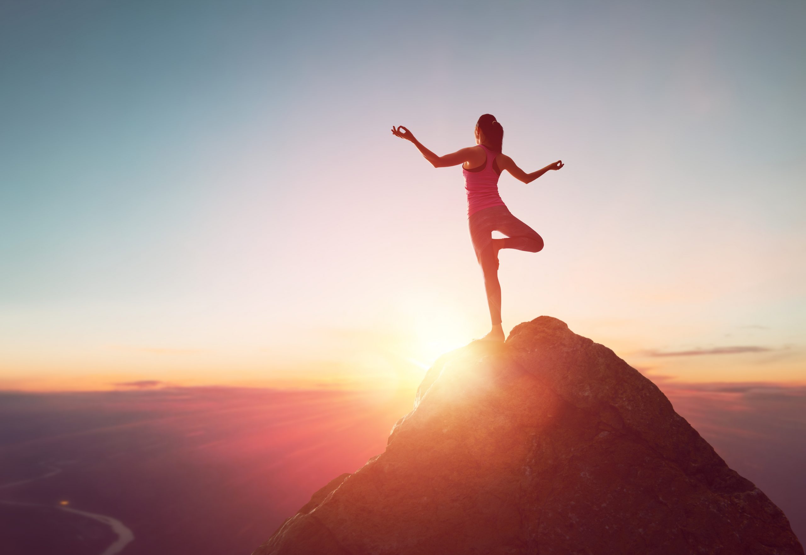 Woman practices yoga and meditates on the mountain.